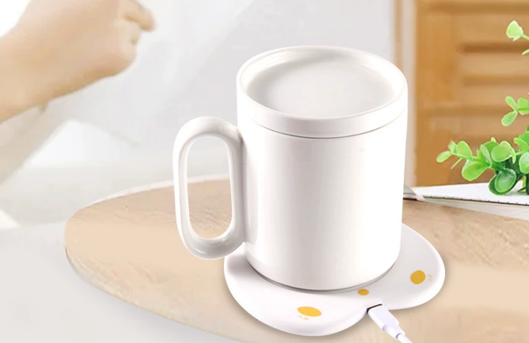 a sleek, modern mug warmer on a desk with a ceramic mug on top, glowing slightly