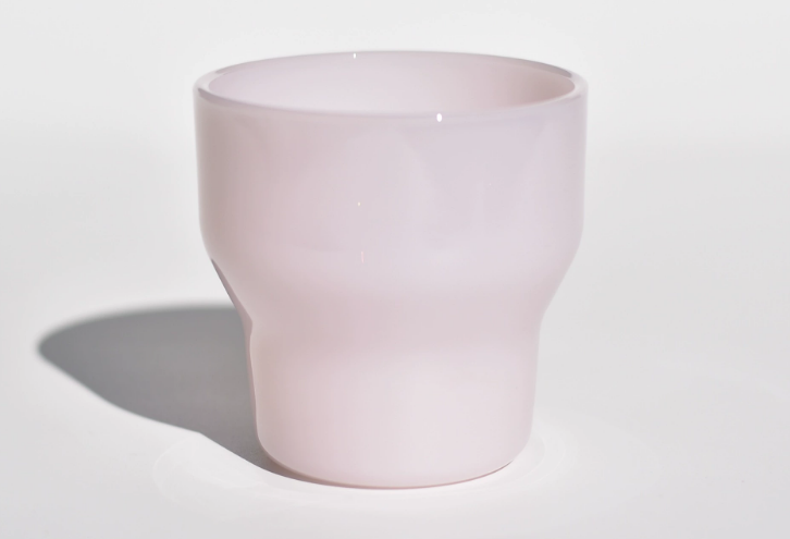 a person holding a piece of milk glass up to a bright light to check for a ring of fire