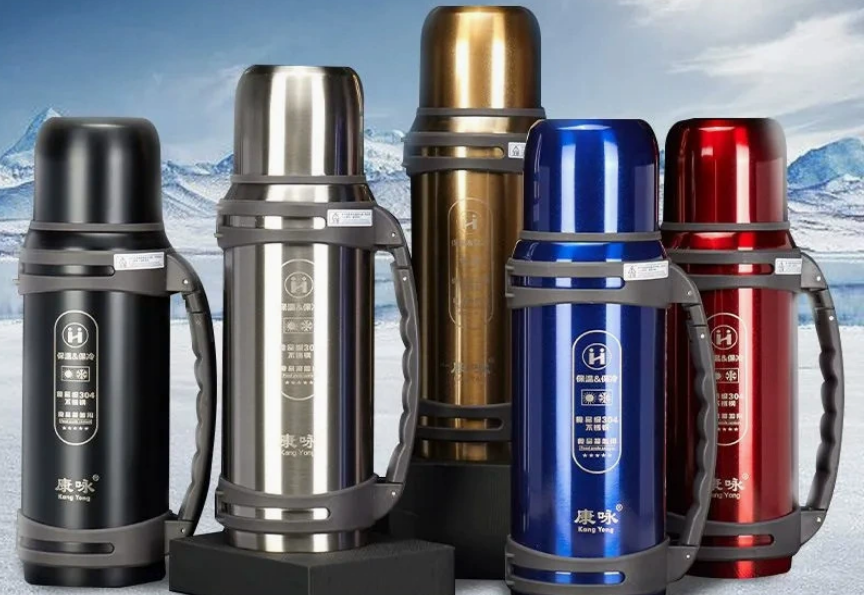 A stainless steel vacuum bottle covered in frost, sitting in a snowy landscape