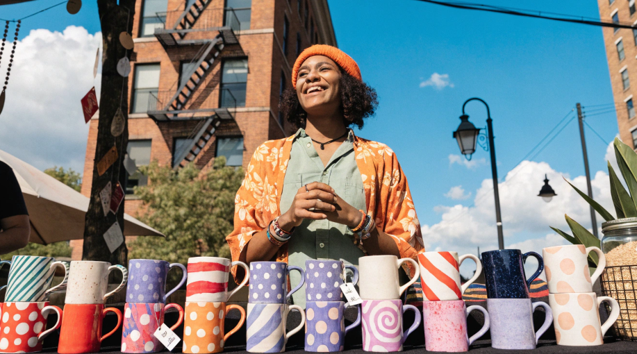 A small business owner proudly displaying their custom-designed mugs at a local market
